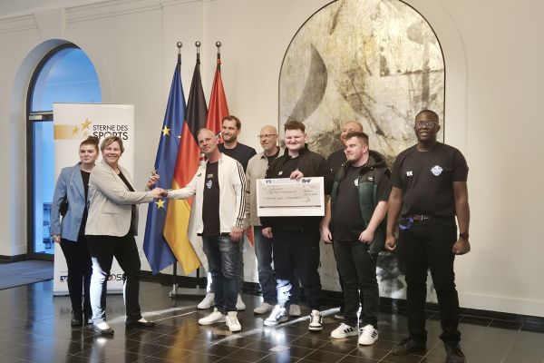 Auf dem Bild sieht man eine Gruppe Menschen, die auf der Bühne stehen und gratuliert werden.