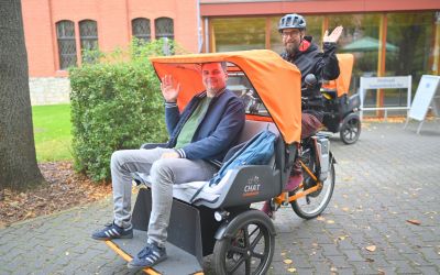 Auf dem Bild sieht man eine Person, die in einer Rikscha gefahren wird.