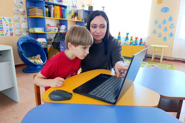 Auf dem Bild sieht man eine Frau und einen Jungen an einem Laptop.