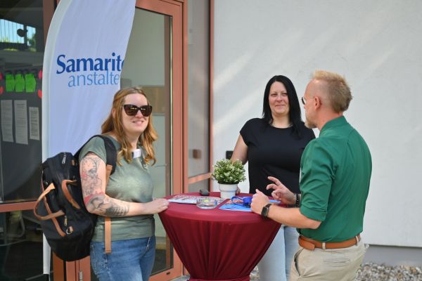 Auf dem Bild sieht man zwei Frauen und einen Mann an einem Stehtisch.