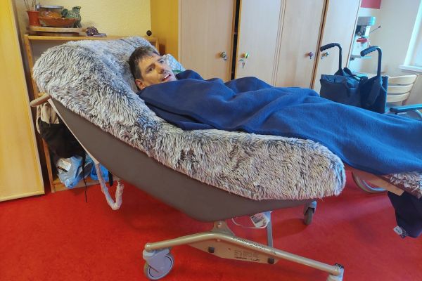 Auf dem Bild sieht man einen Bewohner in einem langgezogenen gemütlichen Sessel liegen.