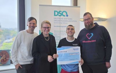 Auf dem Bild sieht man vier Personen, die einen sehr großen Spendenscheck halten.