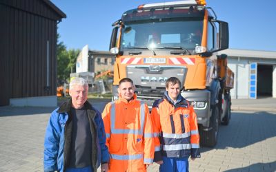 Auf dem Bild sieht man drei Männer vor einem großen LKW.