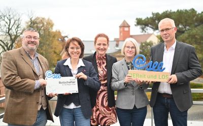 Auf dem Bild sieht man zwei Männer und drei Frauen wie sie in die Kamera lachen.