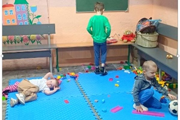 Auf dem Bild sieht man drei Kinder in einem Kita-Raum.