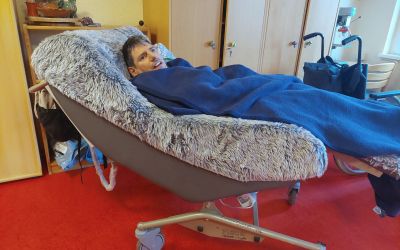 Auf dem Bild sieht man einen Bewohner in einem langgezogenen gemütlichen Sessel liegen.