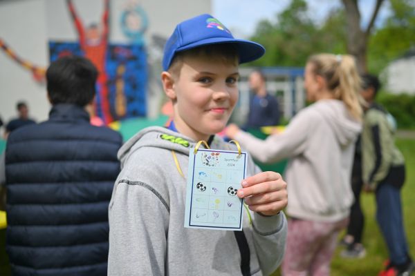 Auf dem Bild sieht man einen Jungen wie er seine Stempelkarte zeigt.