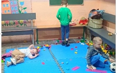 Auf dem Bild sieht man drei Kinder in einem Kita-Raum.