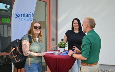 Auf dem Bild sieht man zwei Frauen und einen Mann an einem Stehtisch.